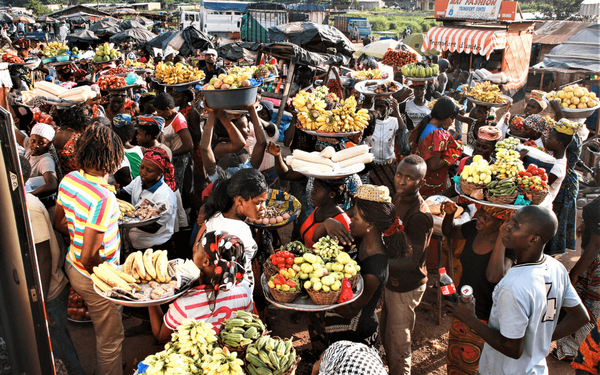 Vibrant Abidjan market scene with vendors balancing colorful fruits on their heads, creating a lively atmosphere. | © GIZ Toni-Kaatz-Dubberke