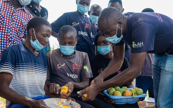 Eine Gruppe von Männern schält gemeinsam Früchte und zeigt, dass Ernährung nicht nur Frauensache ist.