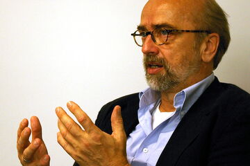 Ein Mann mit Brille und Bart gestikuliert intensiv während eines Gesprächs.