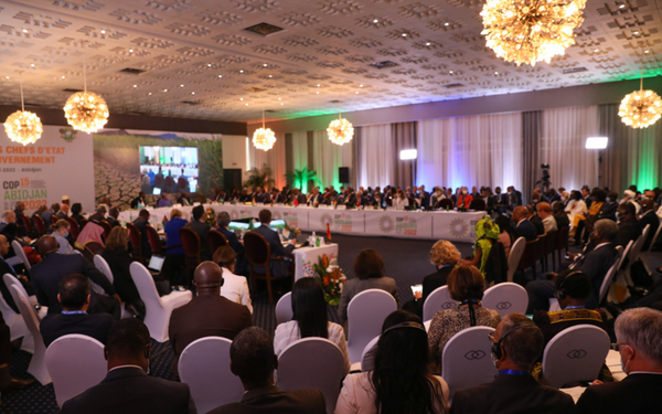 Delegierte sitzen in einem großen Konferenzraum bei der UNCCD COP15 in Abidjan, um Umweltstrategien zu diskutieren.