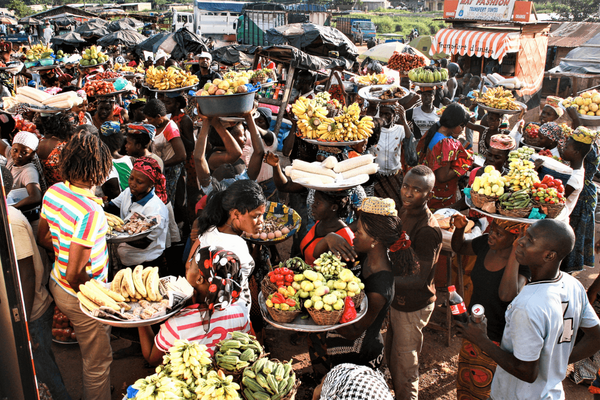 Vibrant Abidjan market scene with vendors balancing colorful fruits on their heads, creating a lively atmosphere. | © GIZ Toni-Kaatz-Dubberke