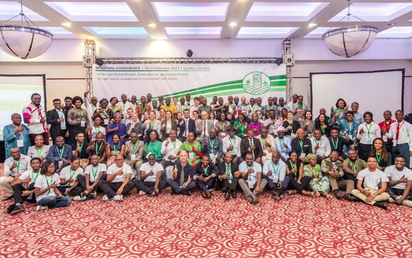 Eine große Gruppe von Menschen posiert lächelnd bei einer Konferenz in Lusaka, 2022, unter einem Banner.