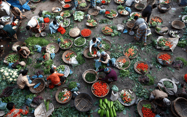 Ein geschäftiger Markt in Bangladesch zeigt Händler, die frisches Gemüse in großen Körben anbieten.