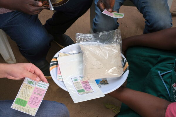 People gather around a bowl holding a package of soy powder, discussing the product information on labels.