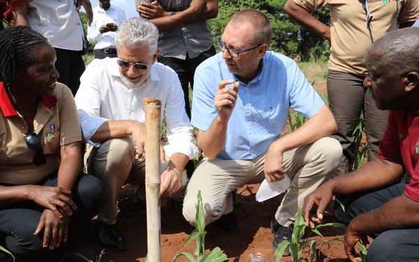 Eine Gruppe von Menschen diskutiert auf einem Feld in Sambia über landwirtschaftliche Techniken.