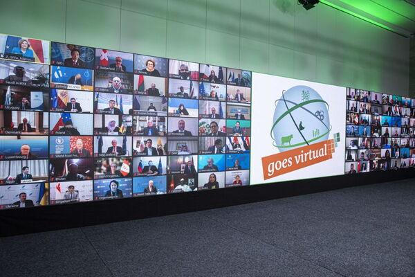 Eine große Videowand zeigt Teilnehmer bei einer virtuellen Konferenz mit dem Slogan "goes virtual".