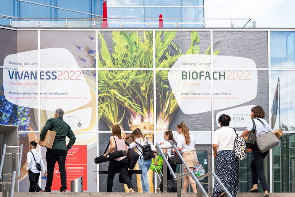 Besucher betreten die NürnbergMesse 2022 für BioFach und Vivaness, vorbei an großen Plakaten der Veranstaltungen.