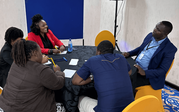 Eine Gruppe von Menschen diskutiert lebhaft an einem runden Tisch während einer TMG-Forschungssitzung.