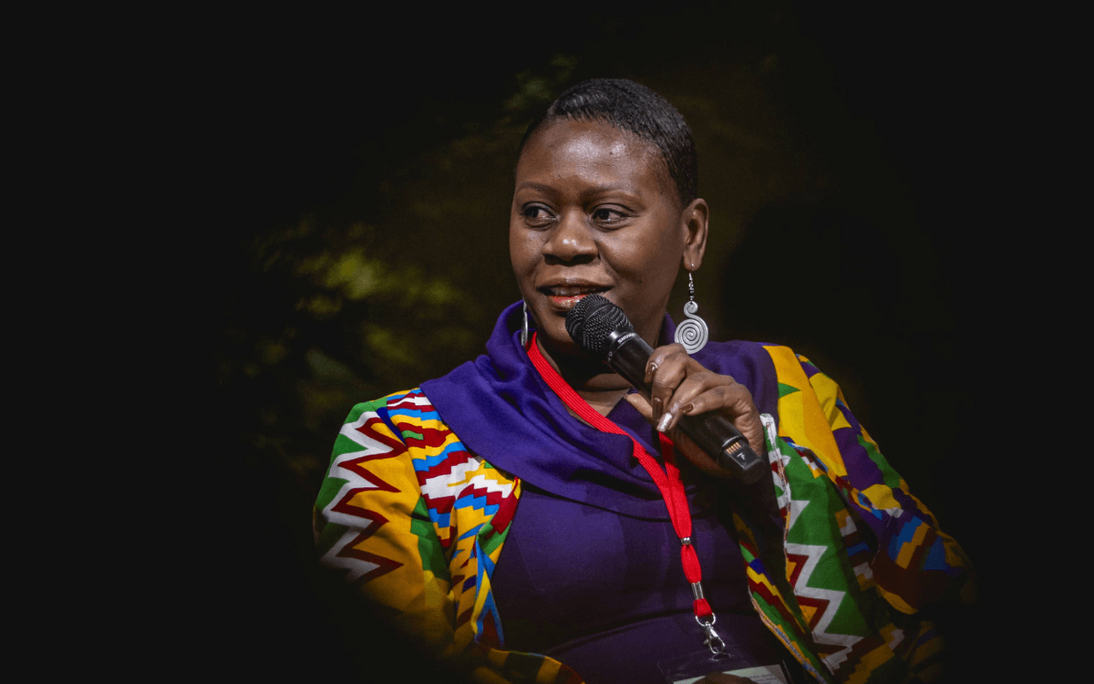 A woman in colorful attire speaks into a microphone during a panel at GIZ Land Week 2025.