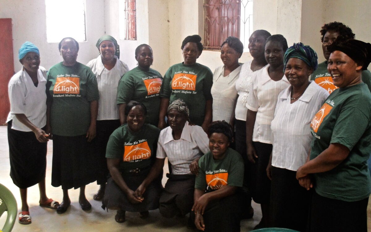 Eine Gruppe von Frauen posiert lächelnd in einem Raum, einige tragen grüne T-Shirts mit dem Aufdruck "d.light".
